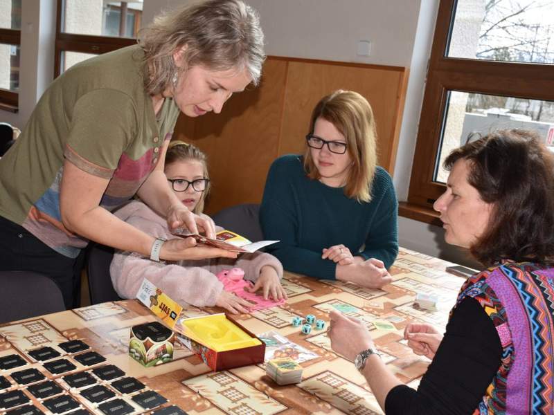Children and adults playing a board game together during a GameON Czechia community activity.
